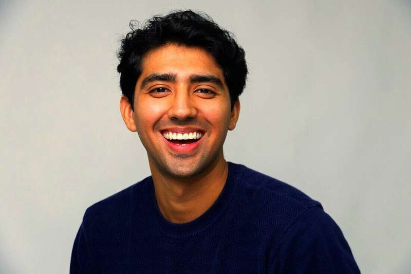 Hombre joven sonriendo con suéter azul oscuro