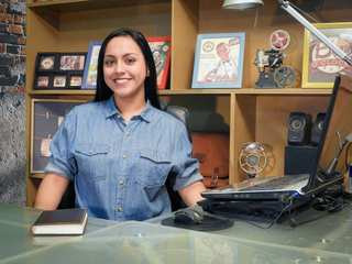 Mujer sonriendo en su escritorio con una notebook y una agenda
