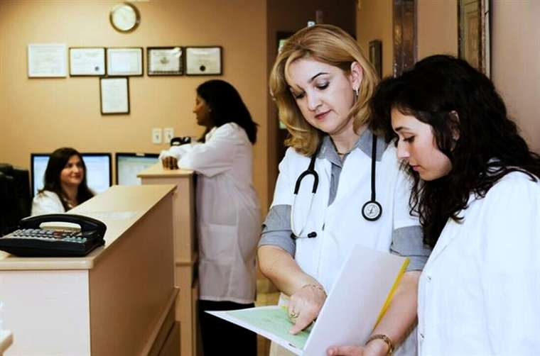 Dos profesionales revisando una carpeta junto a la recepción de un consultorio