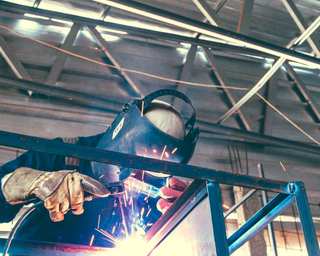 Soldador con máscara y guantes soldando una estructura metálica
