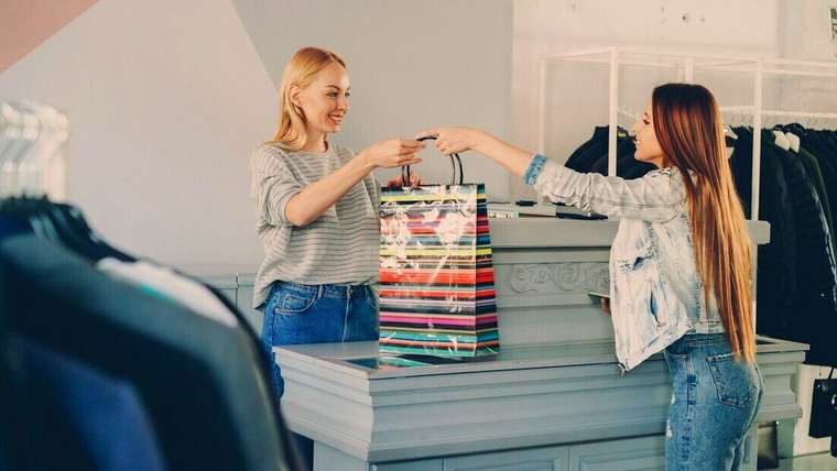 Vendedora entregando una bolsa de compras a una clienta