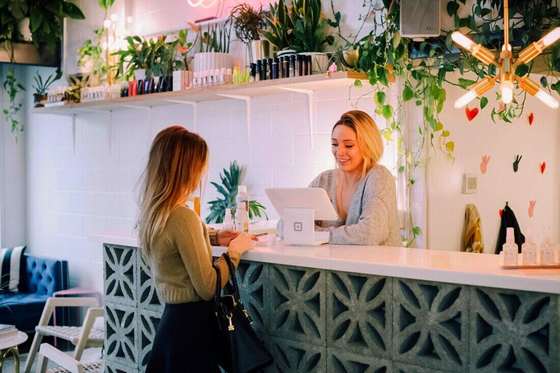 Dos mujeres conversando en el mostrador de un local con plantas