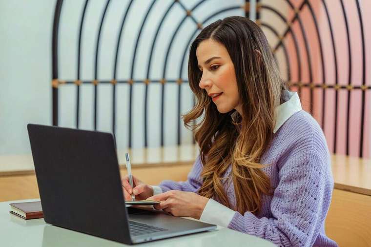 Mujer tomando notas junto a su notebook